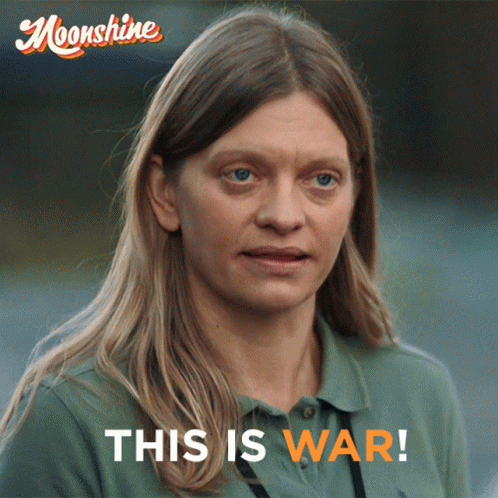 A Woman In A Green Shirt With The Words This Is War On The Bottom GIF