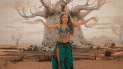 A Woman In A Green Skirt Is Dancing In Front Of A Tree GIF