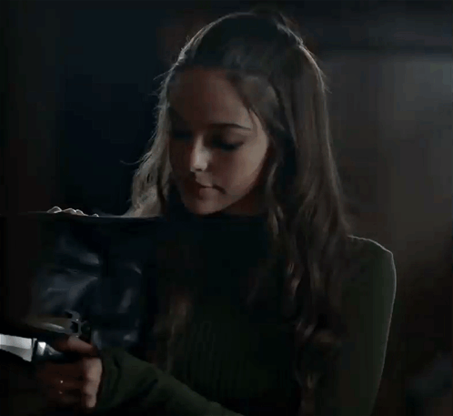 A Woman In A Green Sweater Is Holding A Black Bag With The Word Sopea On The Bottom Right GIF