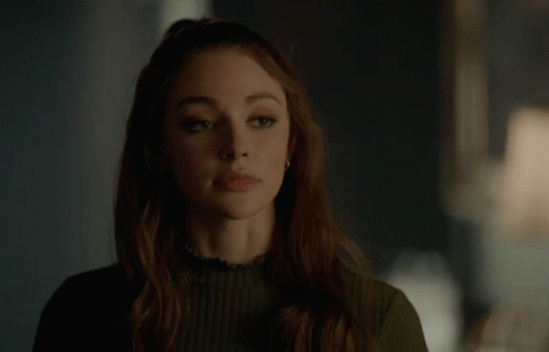 A Woman In A Green Sweater Is Making A Funny Face GIF