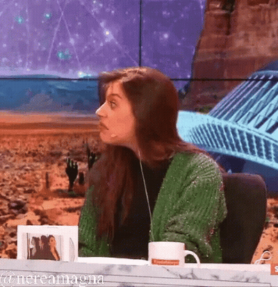 A Woman In A Green Sweater Is Sitting At A Table With A Mug That Says ' Nevada ' On It GIF