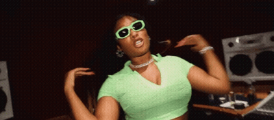 A Woman In A Green Top And Sunglasses Is Dancing GIF