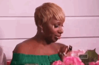 A Woman In A Green Top Is Holding A Pink Flower And Crying . GIF