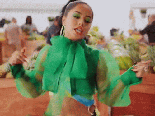 A Woman In A Green Top Is Standing In Front Of A Market . GIF