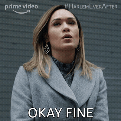 A Woman In A Grey Coat Says Okay Fine In Front Of A Wall GIF