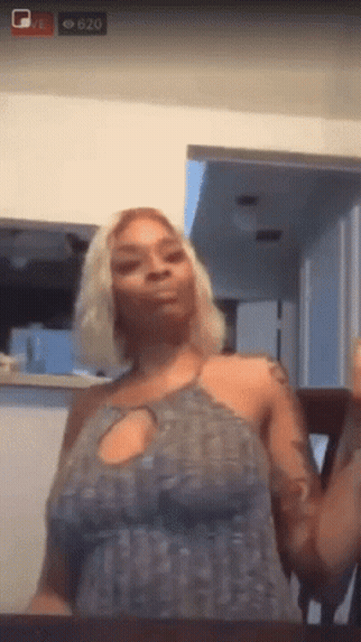 A Woman In A Grey Dress Is Sitting At A Table In Front Of A Screen That Says 620 On It GIF