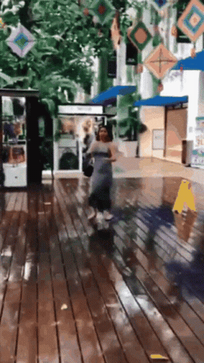 A Woman In A Grey Dress Is Walking On A Wet Floor GIF