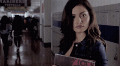 A Woman In A Hallway With A Sign That Says Mariners GIF