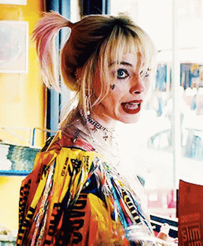 A Woman In A Harley Quinn Costume Stands In Front Of A Window . GIF