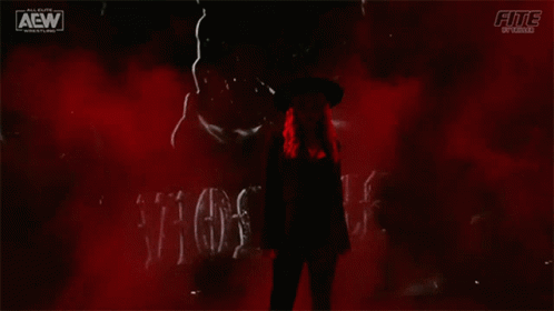 A Woman In A Hat Is Standing In Front Of A Sign That Says Violence . GIF