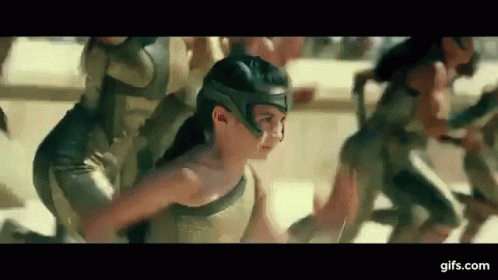 A Woman In A Helmet Is Running With A Group Of People In Armor . GIF