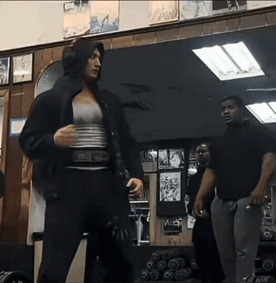 A Woman In A Hooded Jacket Is Standing In Front Of A Mirror GIF