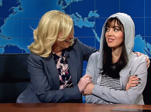 A Woman In A Hoodie Is Being Hugged By Another Woman GIF