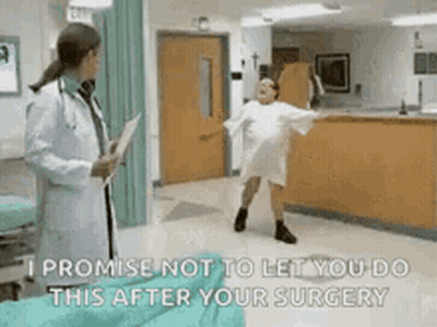 A Woman In A Hospital Gown Is Dancing In Front Of A Doctor Who Is Holding A Clipboard . GIF