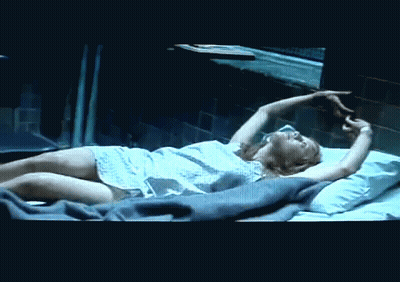 A Woman In A Hospital Gown Is Laying On A Bed GIF