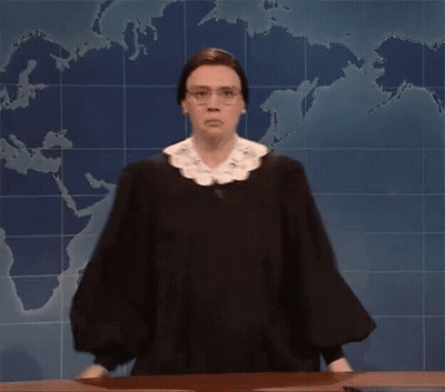 A Woman In A Judge 'S Robe And Glasses Is Standing In Front Of A Map Of The World . GIF