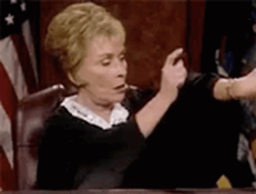 Woman Judge Sitting In Court In Front Of Flag GIF