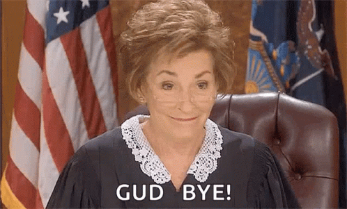 A Woman In A Judge 'S Robe Is Sitting In Front Of An American Flag And Saying Good Bye . GIF