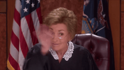 A Woman In A Judge 'S Robe Is Waving Her Hand In Front Of An American Flag GIF