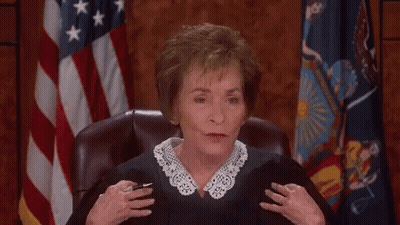 A Woman In A Judge 'S Robe Laughs In Front Of An American Flag GIF