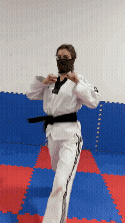 A Woman In A Karate Uniform Is Wearing A Black Mask GIF