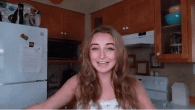 A Woman In A Kitchen With A White Refrigerator And A Microwave GIF