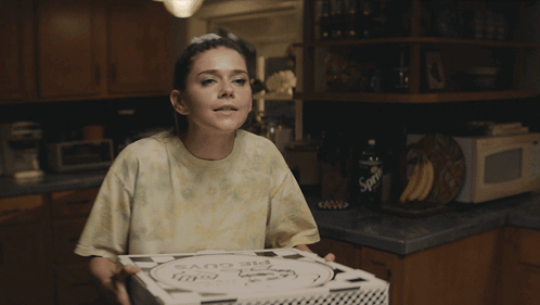 A Woman In A Kitchen With The Words Booyah On Her Shirt GIF