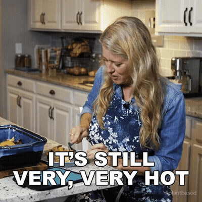 A Woman In A Kitchen With The Words " It 'S Still Very Very Hot " GIF