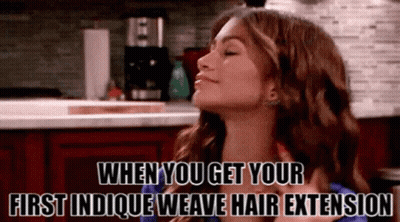 A Woman In A Kitchen With The Words When You Get Your First Indicque Weave Hair Extension GIF