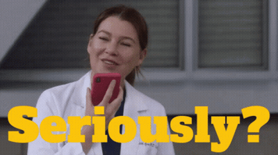 A Woman In A Lab Coat Is Holding A Cell Phone In Front Of The Words Seriously ? GIF