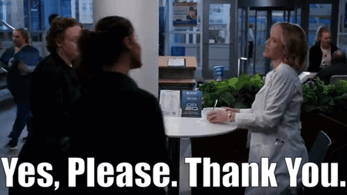 A Woman In A Lab Coat Is Sitting At A Table Talking To A Man In A Black Shirt .. GIF