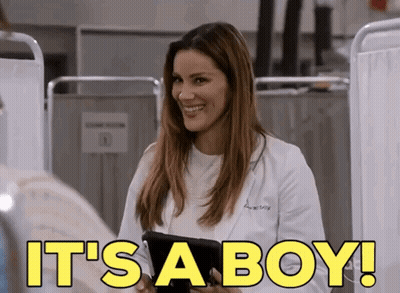 A Woman In A Lab Coat Is Smiling And Holding A Tablet With The Words It 'S A Boy Written On It GIF