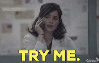 A Woman In A Lab Coat Is Talking On A Cell Phone And The Words Try Me Are Displayed . GIF