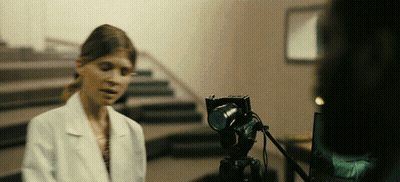 A Woman In A Lab Coat Is Talking To A Camera GIF