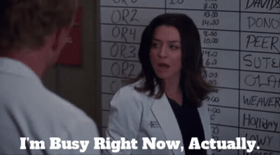 A Woman In A Lab Coat Is Talking To A Man In Front Of A White Board That Says I 'M Busy Right Now GIF