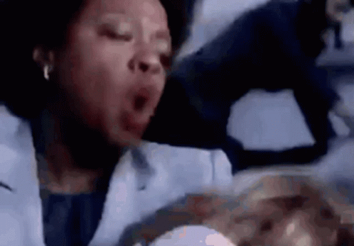 A Woman In A Lab Coat Is Yawning While Holding A Baby In Her Arms . GIF