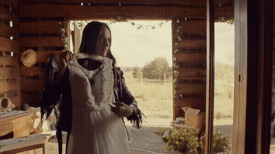 A Woman In A Leather Jacket Holds A White Dress GIF