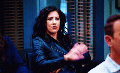 A Woman In A Leather Jacket Is Clapping Her Hands In A Room With Other People GIF