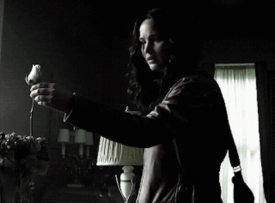 A Woman In A Leather Jacket Is Holding A Rose In Her Hand GIF