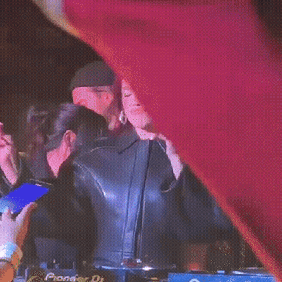 A Woman In A Leather Jacket Is Standing In Front Of A Pioneer Dj Machine . GIF