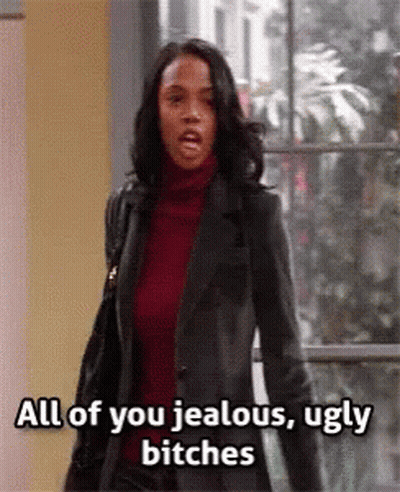 A Woman In A Leather Jacket Is Standing In Front Of A Window . GIF