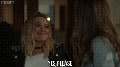 A Woman In A Leather Jacket Is Talking To Another Woman In A Room And Saying `` Yes Please '' . GIF