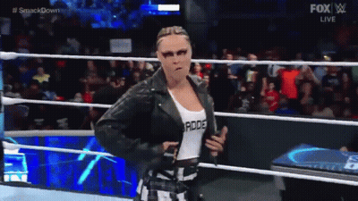 A Woman In A Leather Jacket Is Walking In A Wrestling Ring . GIF