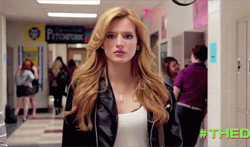 A Woman In A Leather Jacket Stands In A Hallway With A Sign That Says Pitchfork GIF