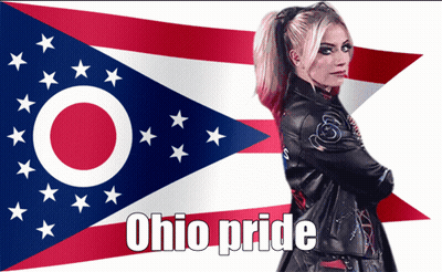 A Woman In A Leather Jacket Stands In Front Of An Ohio Pride Flag GIF
