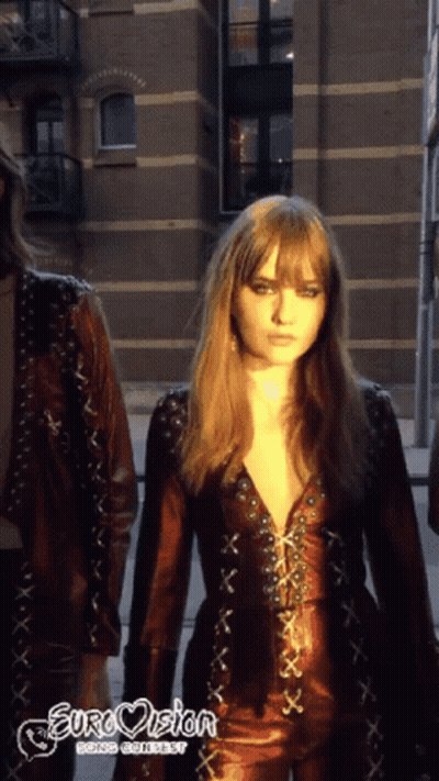 A Woman In A Leather Outfit With Eurovision Going Contest Written On The Bottom Right GIF