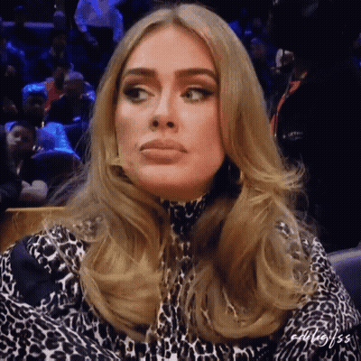A Woman In A Leopard Print Dress Is Sitting In A Crowd Of People GIF