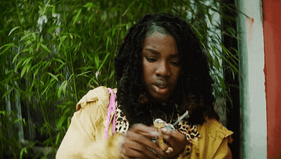 A Woman In A Leopard Print Jacket Is Smoking A Cigarette . GIF