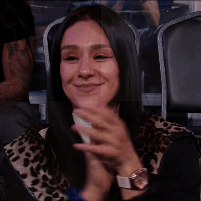 A Woman In A Leopard Print Shirt Is Smiling And Clapping GIF