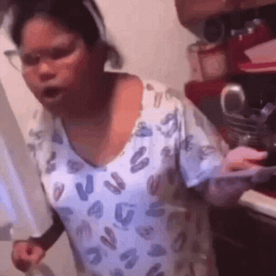 A Woman In A Leopard Print Shirt Is Standing In A Kitchen Holding A Knife . GIF
